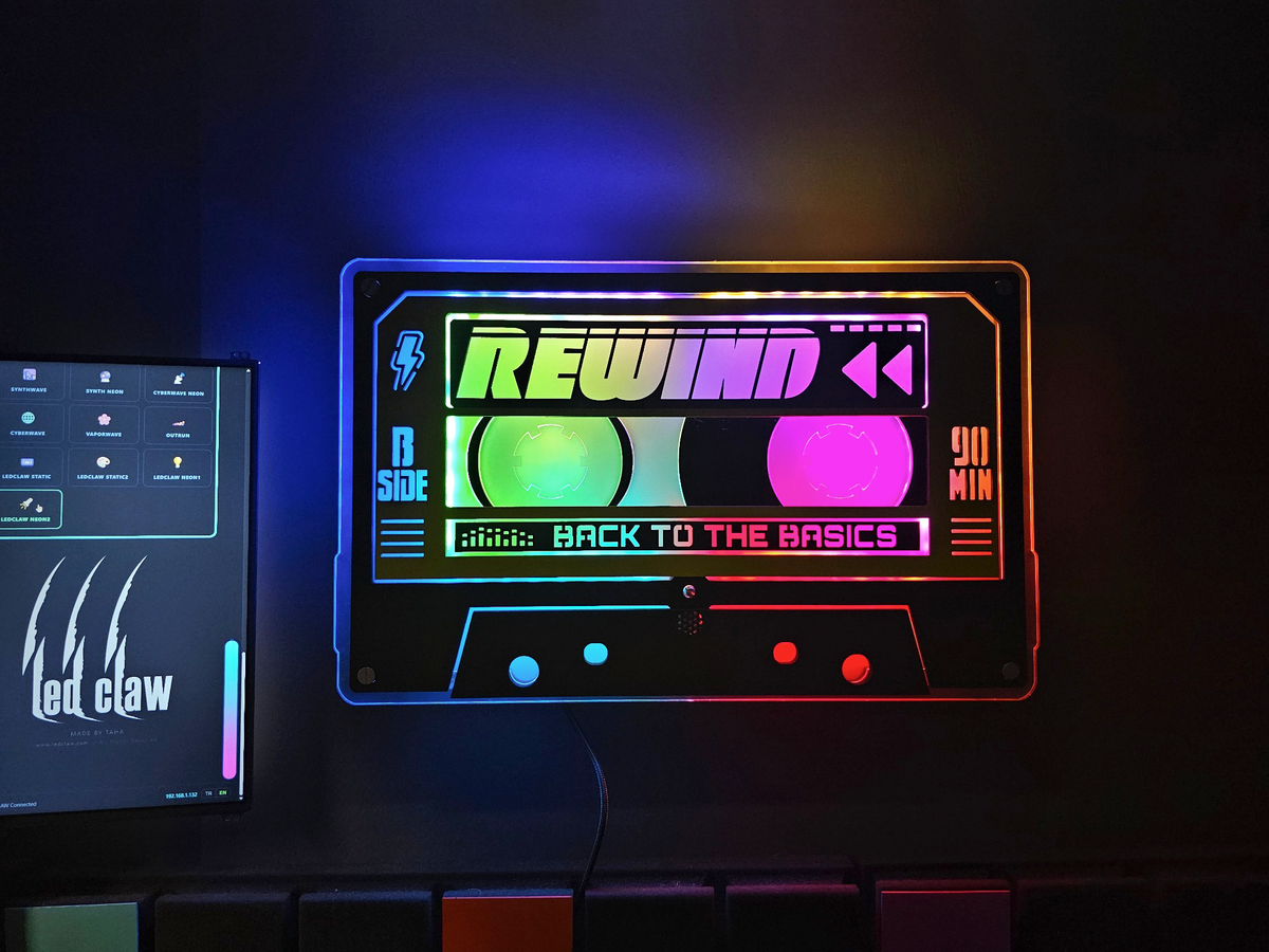 Custom REWIND cassette lit in rainbow colors on a dark wall